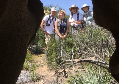 4 hikers standing outside hole in rock