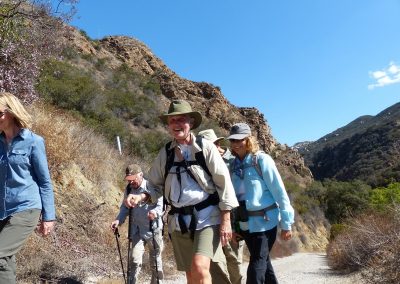 5 hikers climbing hill on dirt road