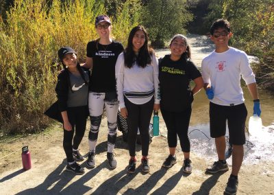 5 students stand in front of a river smiling