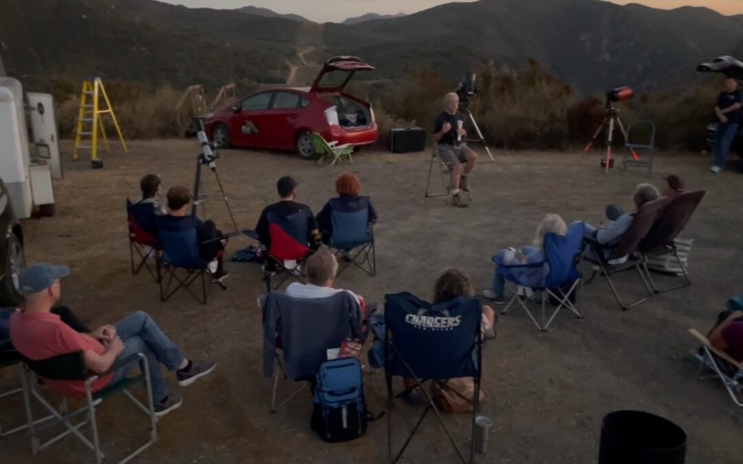 group of 25 people sitting outside at dusk