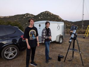 two people standing outside with telescope 